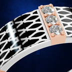 A close-up of a ring featuring a wide white band with a black geometric lattice pattern, a rose gold side plate, and three clear round-cut gemstones.