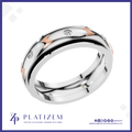 A polished two-tone wedding band ring by Platiszem, featuring a silver-toned main body, rose gold chevron accents, and small clear pavé-set diamonds. The ring is displayed on a white background with a blue border, and the Platiszem brand logo is visible at the bottom.