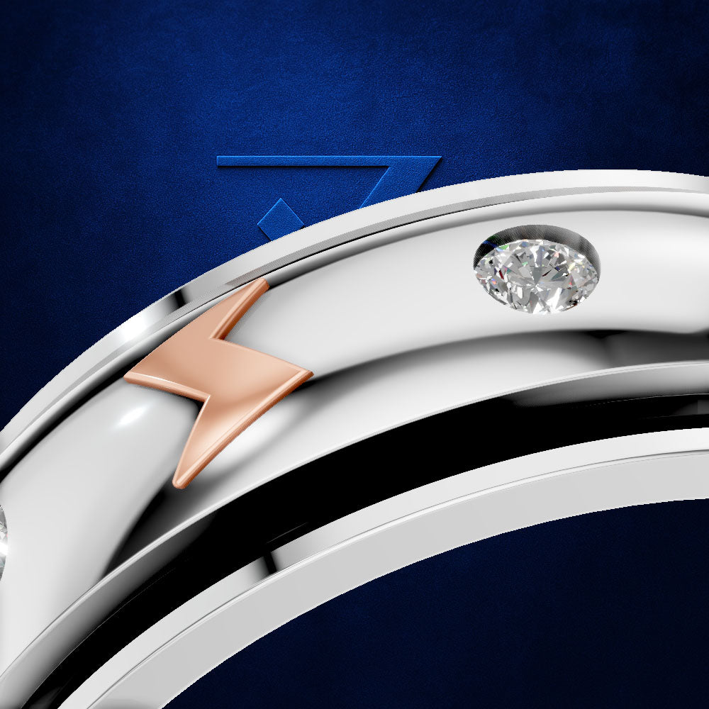 A close-up of a polished silver-toned ring band featuring a rose gold lightning bolt motif and a small round clear gemstone, set against a dark blue textured background.