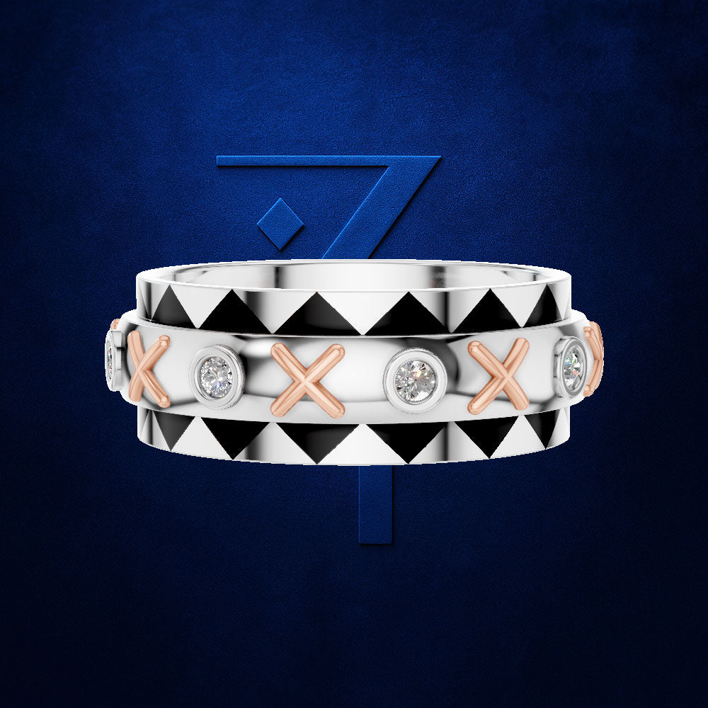 A double-band ring set in silver and rose gold, featuring a top band with a black and white geometric triangle pattern and a bottom band with alternating rose gold X-shaped links and round clear gemstones, set against a dark blue textured background with a blue stylized '7' logo.