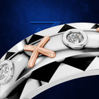 Close-up of a curved silver-toned ring with a rose-gold cross motif and round bezel-set clear stones, shown against a dark blue background.