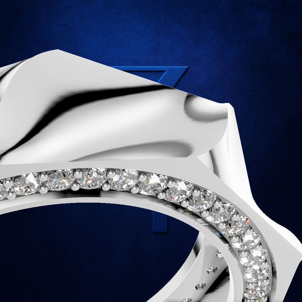A close-up studio shot of a polished silver-toned ring with a curved row of clear gemstones along the band, set against a deep blue textured background.