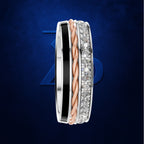 A slim three-band ring set featuring a polished silver band with a black inlay, a twisted rose gold band, and a silver band paved with clear cubic zirconia stones, set against a dark blue textured background.