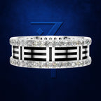 A silver ring with a bold black and white geometric pattern and rows of clear gemstones, set against a dark blue textured background with a blue stylized 'Z' logo behind it.