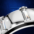 A close-up studio shot of a polished silver-toned ring with rectangular clear gemstones, set against a textured dark blue background.