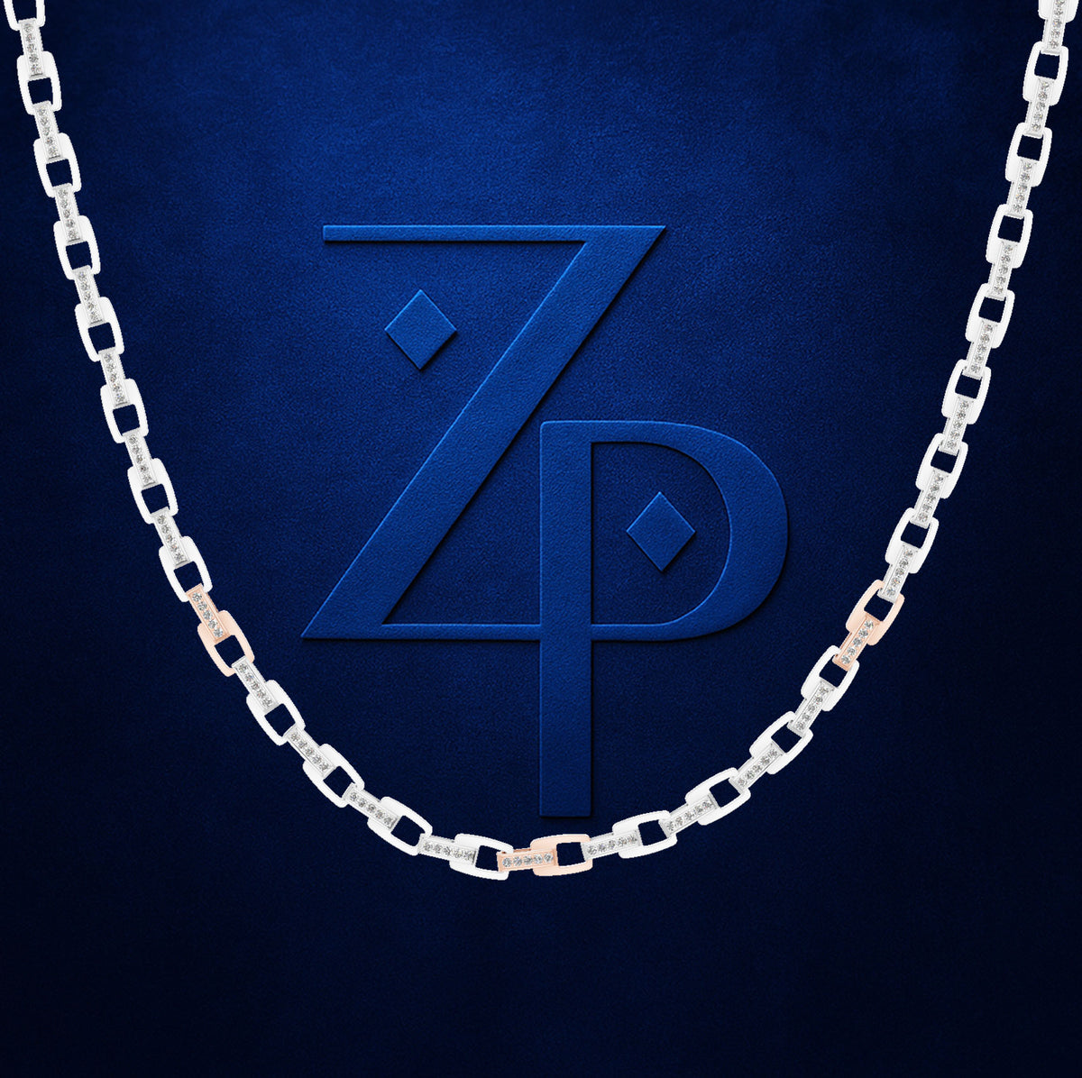 A silver-toned chain necklace with alternating square links and small rose gold accent links, draped in a U-shape over a textured dark blue background with a matching embossed 'ZP' logo.