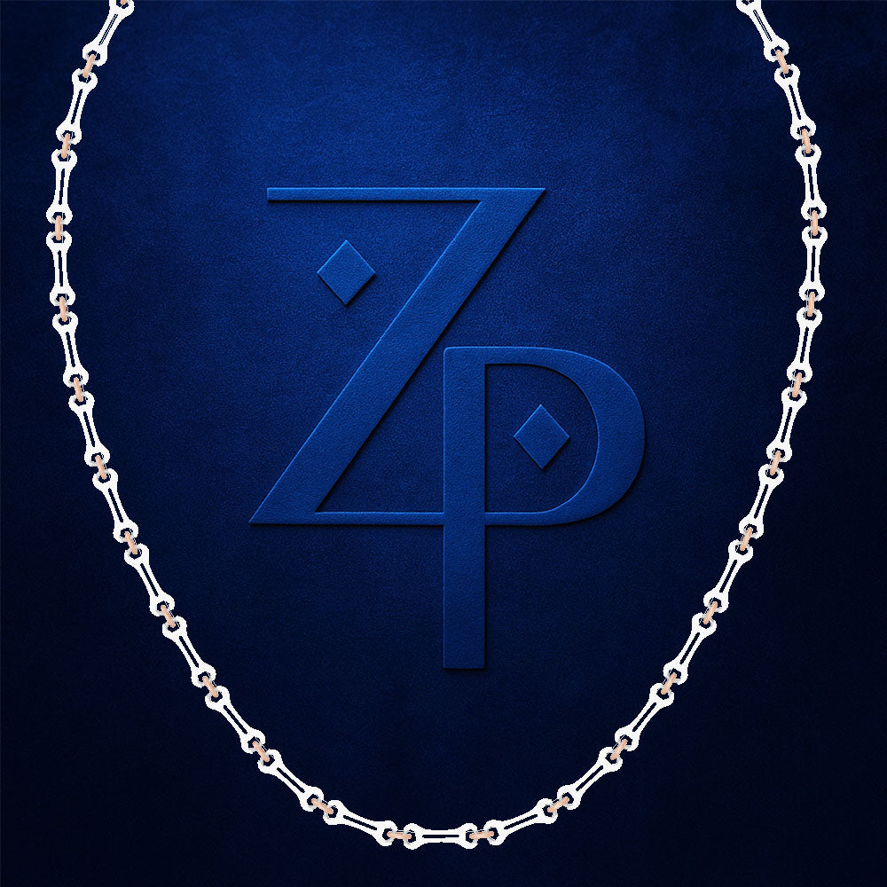 A silver chain necklace arranged in an oval shape against a textured dark blue background, framing a large embossed stylized 'ZP' monogram.
