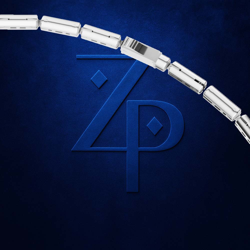 A close-up of a silver-toned cylindrical link chain, likely a bracelet or necklace, arcing across a dark textured blue background with a large embossed stylized 'ZP' logo behind it.