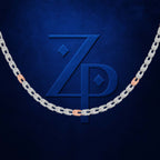 A close-up of a silver-toned chain necklace with rose gold accent links, arranged in a U-shape against a textured dark blue background. A large embossed 'ZP' monogram is centered behind the chain.