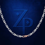 A silver chain necklace with a single rose gold accent link, draped in a U-shape against a textured dark blue background with a matching embossed 'ZP' logo.