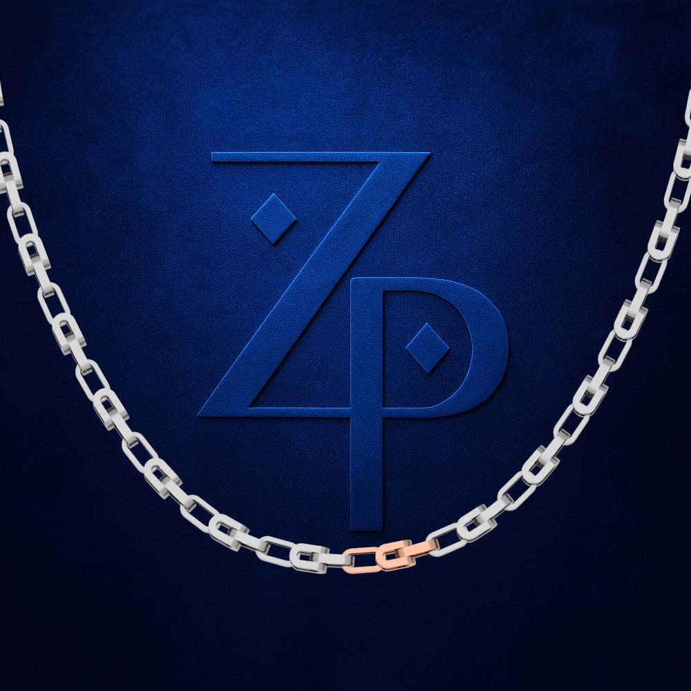 A silver chain necklace with a single rose gold accent link, draped in a U-shape against a textured dark blue background with a matching embossed 'ZP' logo.