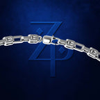 A close-up of a polished silver chain with rectangular links and a lobster clasp, set against a dark textured blue background with a large embossed stylized 'ZP' logo.