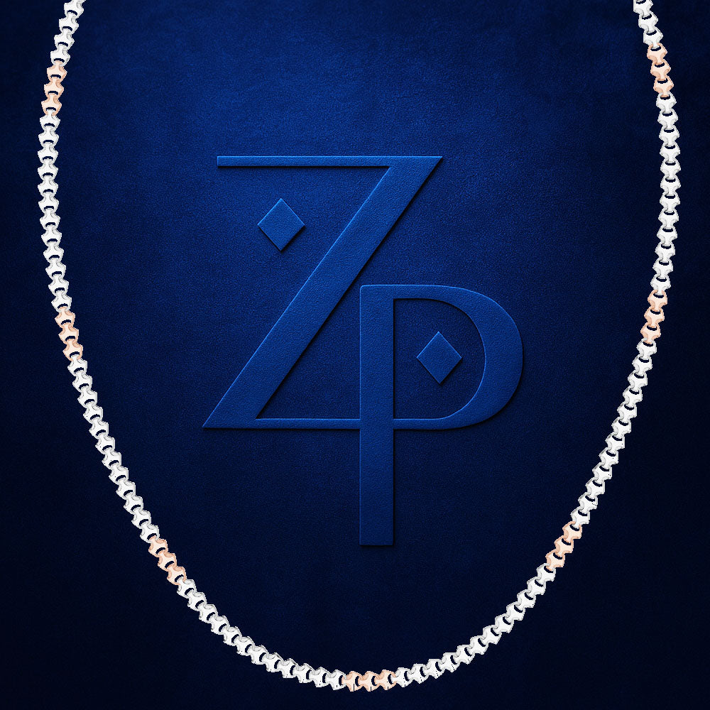 A close-up of a chain necklace with alternating silver and rose gold links, arranged in an oval shape against a textured dark blue background. A large embossed 'ZP' monogram is visible in the center.