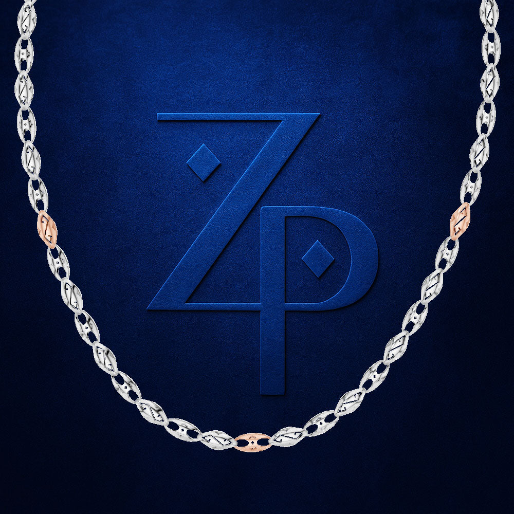A silver-toned chain necklace with alternating oval and diamond-shaped links, accented by rose gold oval links, displayed against a textured dark blue background with a large embossed 'ZP' logo.