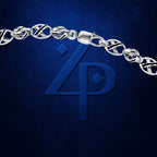 A close-up of a silver chain bracelet with a lobster clasp, draped across a dark blue textured background with a large embossed blue monogram logo underneath.