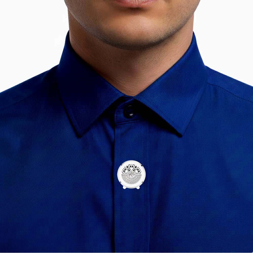 A close-up of a man wearing a royal blue collared dress shirt, focusing on the button placket where a small round silver pin is attached.