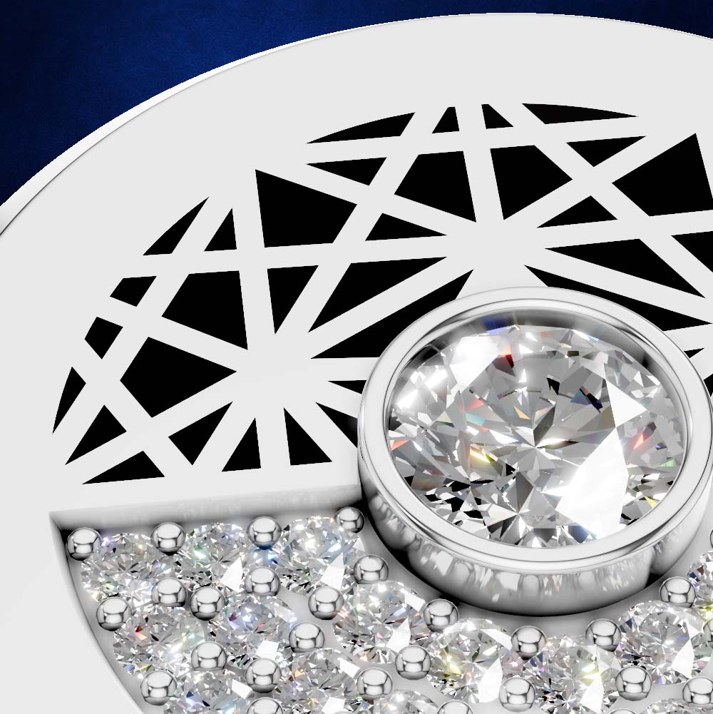 Close-up of a silver-toned jewelry piece featuring a large round clear gemstone in a bezel setting, surrounded by smaller sparkling stones and a geometric cutout pattern on a white curved surface.