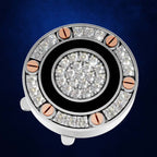 A circular silver-toned jewelry piece with a central cluster of clear gemstones, surrounded by a black ring and outer halo of square-cut clear stones, accented by six rose-gold-toned screws on a dark blue background.