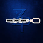 A silver-toned cylindrical jewelry piece with multiple black gemstones and a peach-colored loop, displayed horizontally against a textured dark blue background with a large stylized 'ZP' logo.