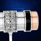 A close-up studio shot of a cylindrical product with a clear crystal-encrusted band, a black ring, and a rose-gold-toned end, set against a dark blue textured background.