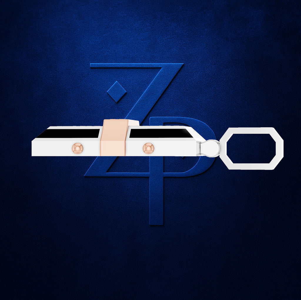 A white and black rectangular keychain or fob with a peach-colored loop and two small metallic circular details, shown against a dark blue textured background with a large stylized blue letter Z behind it.