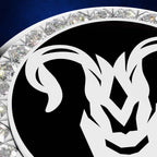 A close-up of a circular black and white ram head emblem or medallion, surrounded by a border of clear faceted gemstones on a dark blue background.