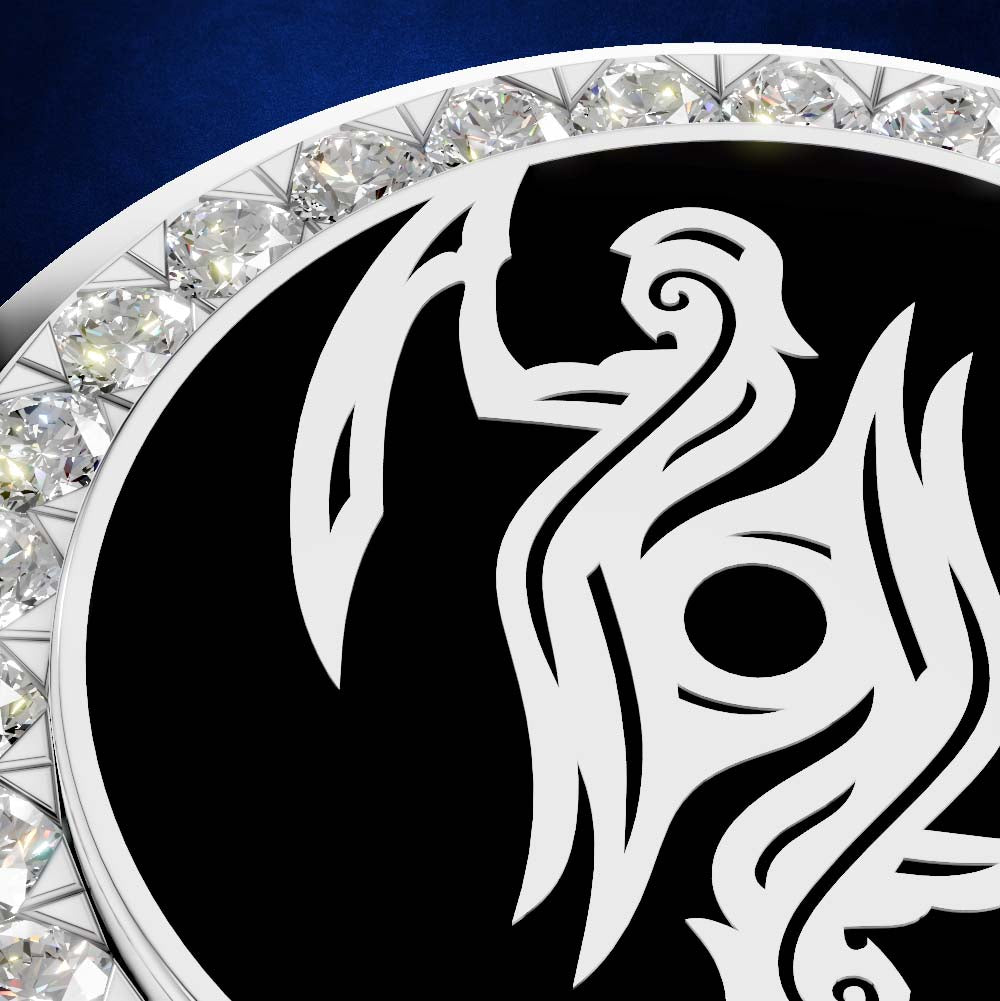 A close-up of a circular silver-toned jewelry piece featuring a bold white stylized bird or phoenix motif on a black center, bordered by clear faceted gemstones against a dark blue background.