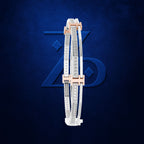 A pair of slim white leather bangles with silver-toned and rose gold metal trim, decorated with rows of clear pavé stones, displayed against a textured dark blue background with a subtle stylized logo.