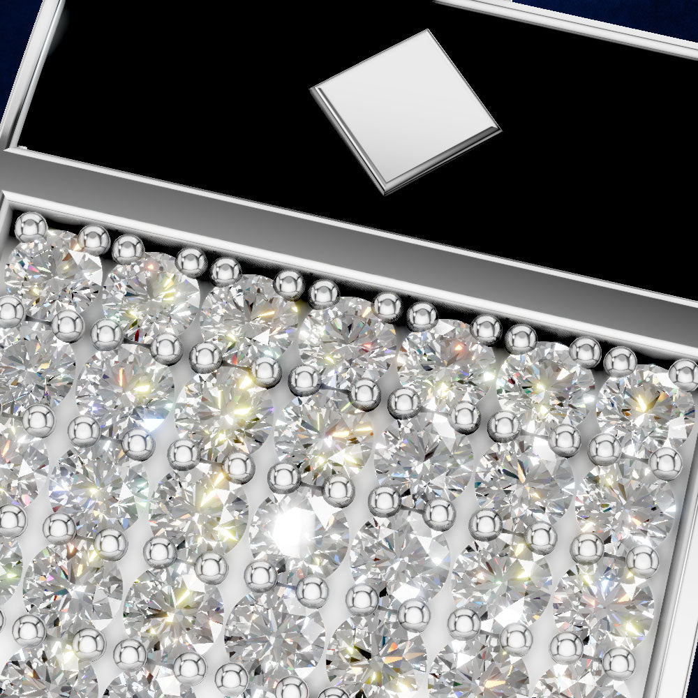 A close-up of a jewelry box filled with many clear round gemstones, with a small square silver sample or card on a black insert in the upper section.