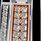 A close-up studio shot of a rectangular jewelry box or tray holding multiple round clear gemstones in prong settings. The center compartment has a peach-pink interior and a row of large clear stones; adjacent compartments show additional clear stones in silver-toned settings.
