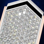 A close-up of a jewelry setting or tray filled with many clear faceted gemstones, framed by a white border and pale pink outer edges against a dark blue background.