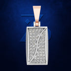 A rectangular pendant necklace featuring a silver-toned frame and a pavé diamond face with a curved rose gold inlay, set against a textured dark blue background.
