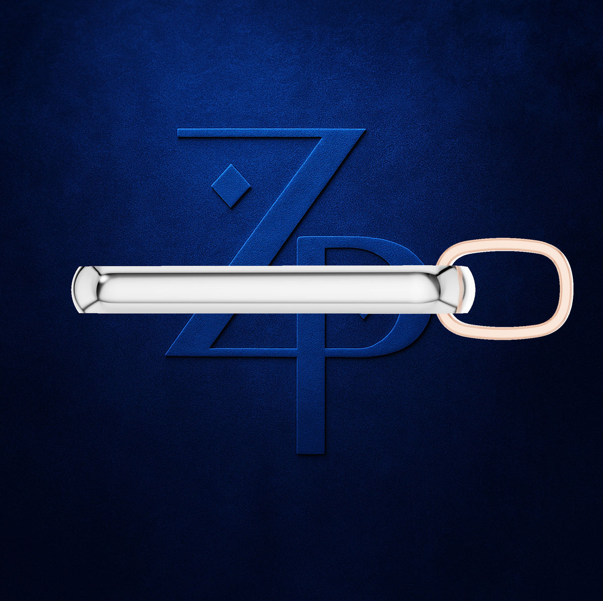 A silver-toned metal tie bar with a rose gold loop, shown horizontally against a textured dark blue background with a matching blue stylized 'ZP' logo behind it.