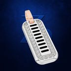 A silver-toned rectangular dog tag pendant with a rose gold loop, set with clear crystals around a central black-and-silver striped pattern, shown on a dark blue textured background.