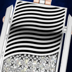 Close-up of a silver-toned jewelry piece with a wavy black-and-white striped top and a row of clear faceted stones along the bottom, shown against a dark blue background.