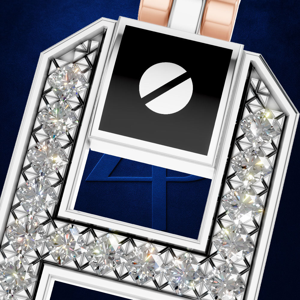 A close-up of a luxury jewelry pendant or brooch featuring a silver-toned geometric frame set with clear faceted gemstones. The center contains a black square with a white circle-and-slash symbol above a deep blue insert showing the number 4.