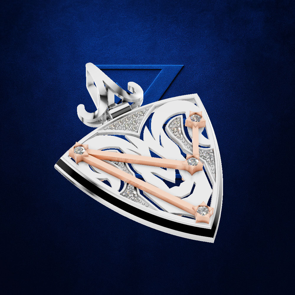 A luxury fashion accessory, likely a pendant or brooch, featuring a shield-like design with silver and white scrollwork, blue inlay, rose gold bars, and clear rhinestones, set against a textured dark blue background.