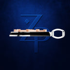 A metallic key-shaped accessory with a polished silver handle and a black central bar, featuring a row of small rose-gold rectangular elements along the top, set against a textured dark blue background with a large stylized blue 'ZP' logo.