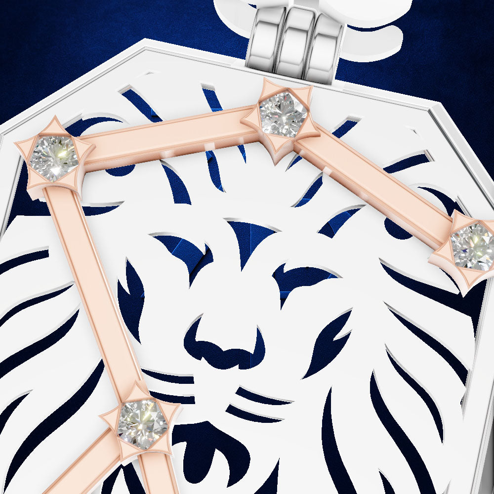 Close-up of a white and navy blue geometric pendant or brooch featuring a stylized lion face cutout, accented with rose gold bars and clear gemstones on a dark blue background.