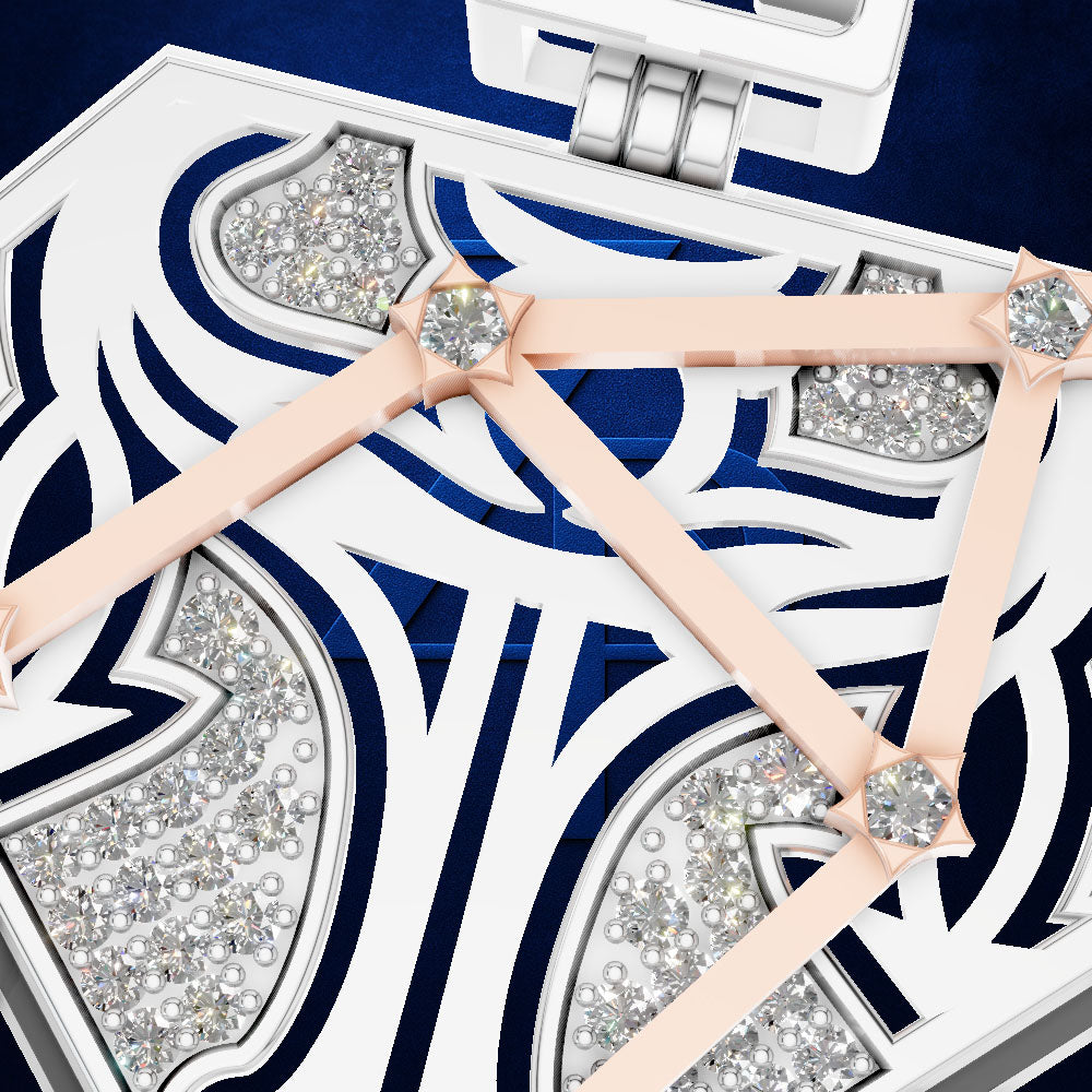 A close-up of a white jewelry box with intricate navy blue cutout patterns, sparkling clear rhinestones, and pale pink ribbon ties with round crystal centers.