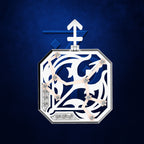An octagonal pendant or brooch featuring intricate white filigree cutouts over a deep blue background, accented with small clear gemstones and a silver-toned border, set against a textured dark blue backdrop.