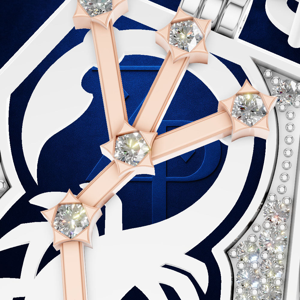 Close-up of a luxury watch dial featuring a white and navy blue shield-like motif with rose gold bars and clear gemstones.