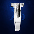 A silver-toned men's ring with a bold geometric design, featuring a central channel set with clear pavé stones and a vertical black inlay, shown against a dark blue textured background with a subtle Avengers logo.