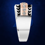 A modern geometric ring featuring a white band, a central rose gold column with three clear gemstones, and black chevron accents on a dark blue textured background.