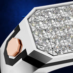 Close-up of a geometric ring with a white and black faceted band, a cluster of clear gemstones in a triangular grid, and a rose gold accent on a dark blue background.