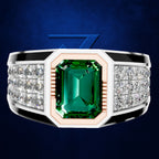 A men's statement ring featuring a large emerald-cut green gemstone in a white and rose gold octagonal setting, flanked by rows of small clear accent stones on a dark blue textured background.