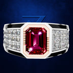 A men's statement ring featuring a large rectangular emerald-cut pinkish-red center gemstone, flanked by rows of clear accent stones on a silver-toned band with black inlays, set against a dark blue textured background.