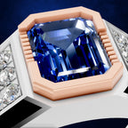 A close-up of a ring featuring a large, faceted blue sapphire gemstone in an octagonal bezel setting with a rose gold-colored metal border and white metal band details accented with small clear stones.