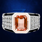 A wide silver-toned ring with a large rectangular peach-orange center stone and rows of clear stones on the shoulders, shown on a dark blue background.