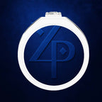 A white circular pendant or medallion with a raised blue monogram design, shown on a textured dark blue background. The top center features a small clear gemstone.